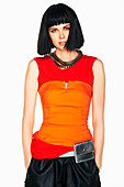 A black-haired woman wearing a long, red top, an orange corset and a black skirt