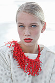 A young blonde woman with red lipstick and a red statement necklace