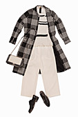 A ruffled blouse, light trousers and a mid-length Prince of Wales check coat, a shoulder bag and shoes
