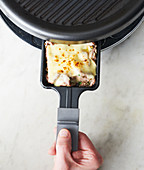 A pan being removed from a raclette