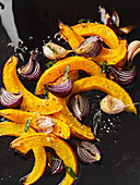 Oven-roasted pumpkin wedges with red onions and garlic (seen from above)