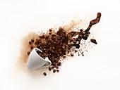 Cup of coffee spilling with liquid and beans coming out