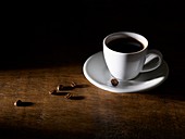 Coffee in coffee cup with beans on wooden table