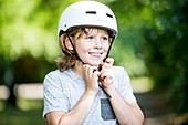 Boy fastening bicycle helmet