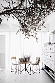 White dining room with vintage furniture and tree branch as decoration