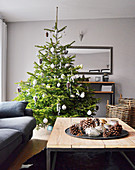 Decorated Christmas tree, Christmas decorations on tray on coffee table and grey couch in living room