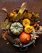 Pumpkins with autumnal leaves in a metal bucket
