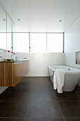 Frei stehende Badewanne und Waschtisch mit Holzverkleidung im Badezimmer