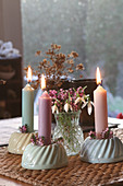 Burning candles in Bundt cake candle holders with snowdrops as table decoration