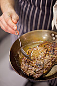 Steak being basted with butter in a pan