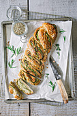 Savoury yeast bread with pesto and herbs on a baking sheet (top view)