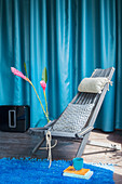 Grey wooden chair and pink flowers in front of blue curtain