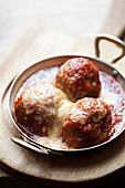 Meatballs in a tomato sauce topped with cheese