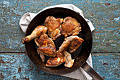Golden chicken thighs and wings in a pan