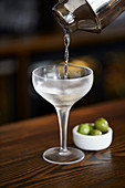 Martini aus Shaker in Glas gießen