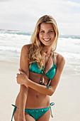 A blonde woman on a beach wearing a turquoise bikini