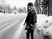 A young woman wearing a jacket, a long shirt and a hat