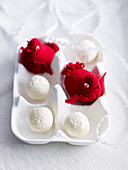 Crocheted red birds and truffle chocolates in a white egg box