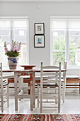 Weiße Landhausstühle um einen Holztisch mit abgenutzter Farbe