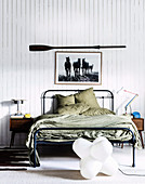 Metal bed with green bedding, above picture with horse motif and paddle