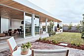 Blick von der Terrasse im Garten auf modernes Haus mit Fensterfront