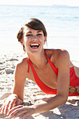 Reife brünette Frau in rotem Badeanzug am Strand