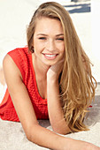 A young blonde woman on a beach wearing a red summer dress