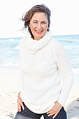 Brünette Frau in weißem Strickpullover am Strand