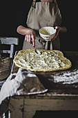Woman putting stuffing on dough while cooking
