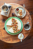 Ricotta-Käsekuchen mit Feigen und Ahornsirup serviert mit Kaffee auf Holztisch (Aufsicht)