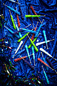 Very colorful assortment of rock candies on a blue velvet surface with sparkly streamers around