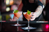 A bartender serving cocktails at a bar