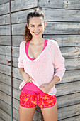 A brunette woman wearing a pink jumper, a top and shorts