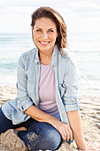 Brünette Frau in Jeansbluse und Jeans am Strand