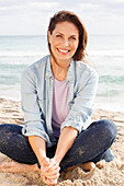 Brunette woman wearing denim blouse and jeans on beach
