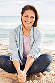 Brünette Frau in Jeansbluse und Jeans am Strand