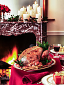 Truthahnbraten auf weihnachtlich gedecktem Tisch am Kaminfeuer