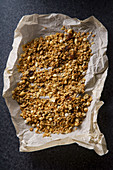 Top view of roasted granola with nuts, flakes and raisins on parchment paper