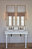 Vintage-style washstand with twin sinks, two mirrors and three wall lamps in bathroom