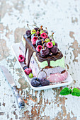 Dreifarbiger Eiskuchen mit Schokoladenglasur, gefrorenen Kirschen und Beeren