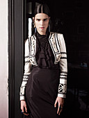 A young brunette woman wearing a Spanish outfit standing against a door frame