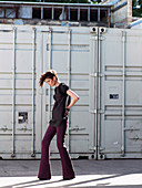 Junge brünette Frau mit Kurzhaarfrisur in lila Hose und grauem Shirt