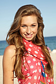 A young blonde woman by the sea wearing a beach towel