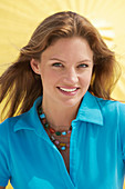 A young brunette woman wearing a blue shirt in front of a yellow parasol