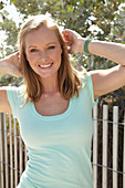 A young blonde woman outside wearing a light-blue top