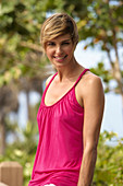 A mature blonde woman with short hair outside wearing a purple top