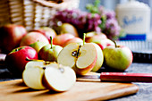 Frische Äpfel, ganz und aufgeschnitten mit Messer auf Holzbrett