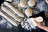 Unbaked rolls and baguettes on a floured work surface