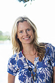 A young blonde woman on a beach wearing a blue-and-white patterned shirt