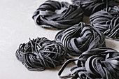 Variety of italian homemade raw uncooked cuttlefish ink black pasta spaghetti and tagliatelle with semolina flour